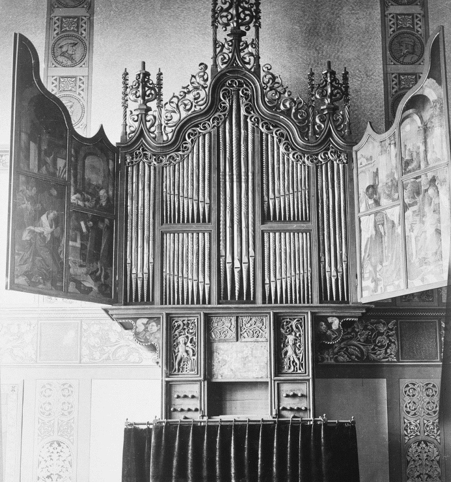 Het orgel met geopende luiken hangt hier nog aan de muur in het Rijksmuseum te Amsterdam.